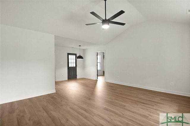 unfurnished living room with a ceiling fan, vaulted ceiling, baseboards, and wood finished floors