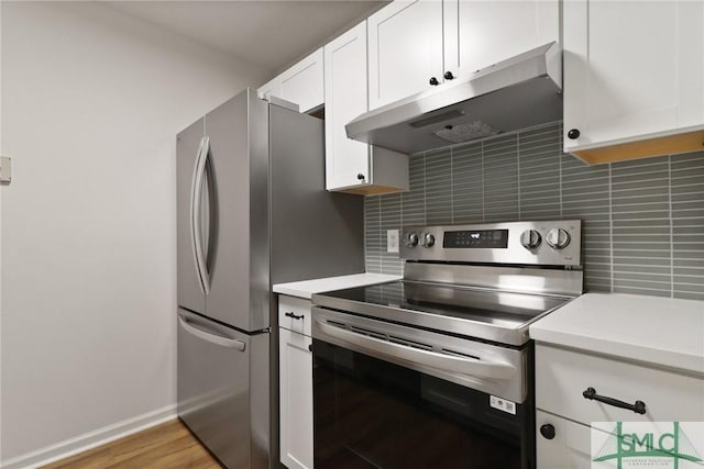 kitchen featuring appliances with stainless steel finishes, under cabinet range hood, light countertops, tasteful backsplash, and white cabinets