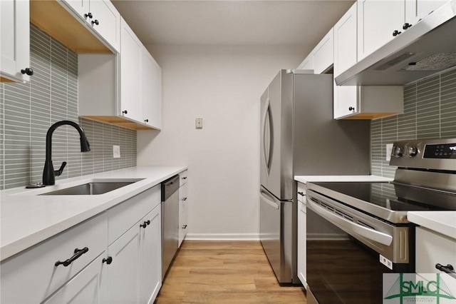 kitchen with appliances with stainless steel finishes, under cabinet range hood, a sink, and backsplash