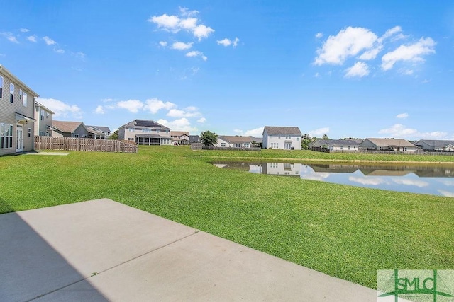 view of yard with a residential view, a patio, and a water view
