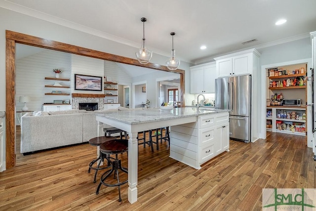 1840 Mccall Rd, Rincon, GA 31326 - kitchen featuring freestanding refrigerator, white cabinetry, light stone counters, an island with sink, and a sink