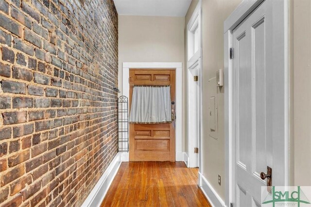 20 W Oglethorpe Ave Unit D, Savannah, GA 31401 - doorway to outside featuring brick wall, dark wood-style floors, and baseboards