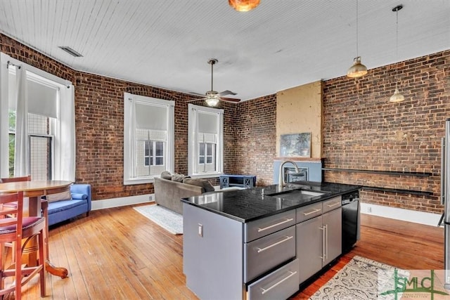 20 W Oglethorpe Ave Unit D, Savannah, GA 31401 - kitchen with a sink, brick wall, light wood-style floors, black dishwasher, and baseboards