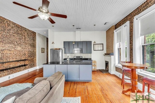 20 W Oglethorpe Ave Unit D, Savannah, GA 31401 - kitchen with appliances with stainless steel finishes, brick wall, dark countertops, a fireplace, and light wood-style flooring