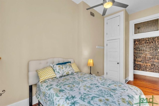 20 W Oglethorpe Ave Unit D, Savannah, GA 31401 - bedroom with baseboards, wood finished floors, brick wall, and a ceiling fan