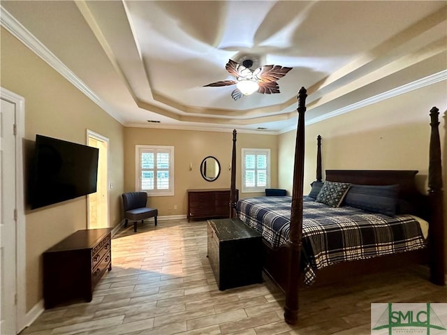 bedroom with a tray ceiling, multiple windows, ornamental molding, baseboards, and light wood-type flooring