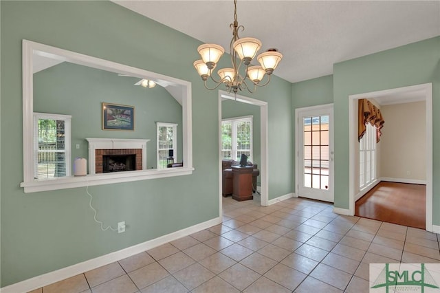 unfurnished dining area featuring a chandelier, a fireplace, tile patterned flooring, and baseboards