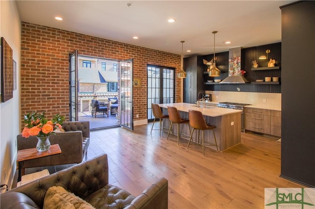 456 Port St, Savannah, GA 31401 - bar featuring high end stainless steel range oven, wall chimney exhaust hood, brick wall, light wood-style flooring, and a sink