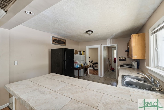3808 Elmdale Ave, Savannah, GA 31405 - kitchen featuring white appliances, a sink, tile counters, a textured ceiling, and light tile patterned flooring