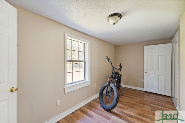 3808 Elmdale Ave, Savannah, GA 31405 - exercise room with wood finished floors, a textured ceiling, and baseboards