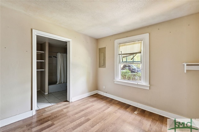 3808 Elmdale Ave, Savannah, GA 31405 - unfurnished bedroom with wood finished floors, a textured ceiling, baseboards, electric panel, and ensuite bathroom