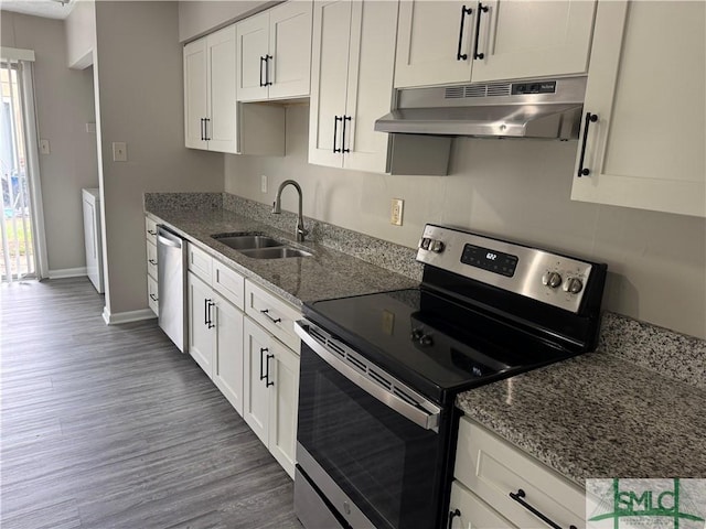 kitchen featuring appliances with stainless steel finishes, under cabinet range hood, a sink, wood finished floors, and baseboards