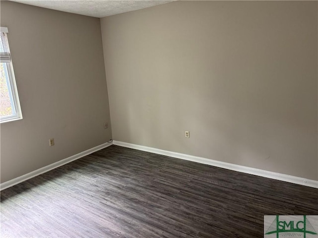 spare room featuring dark wood-type flooring, baseboards, and a textured ceiling