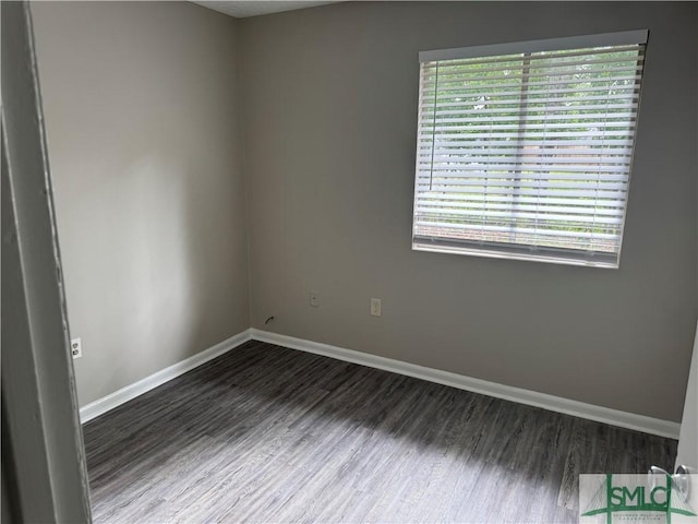 empty room featuring dark wood-style flooring, plenty of natural light, and baseboards