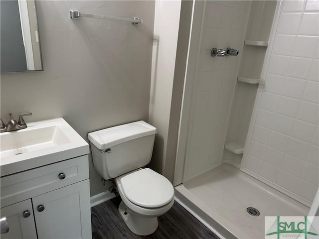 bathroom featuring toilet, a stall shower, vanity, and wood finished floors
