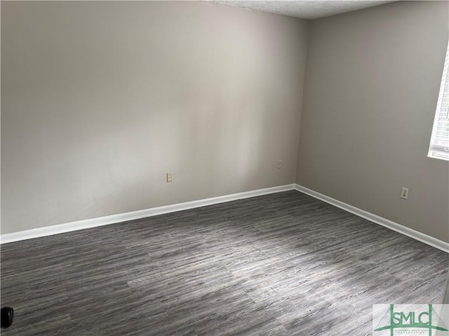 unfurnished room with dark wood-style floors, baseboards, and a textured ceiling