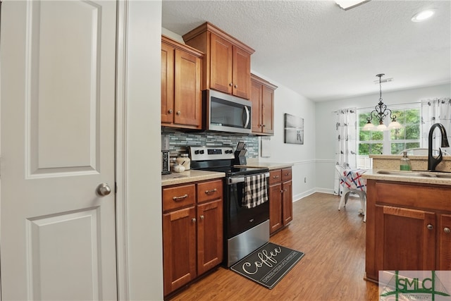 13 Sassafras Ln, Midway, GA 31320 - kitchen with stainless steel appliances, a sink, wood finished floors, light countertops, and a textured ceiling