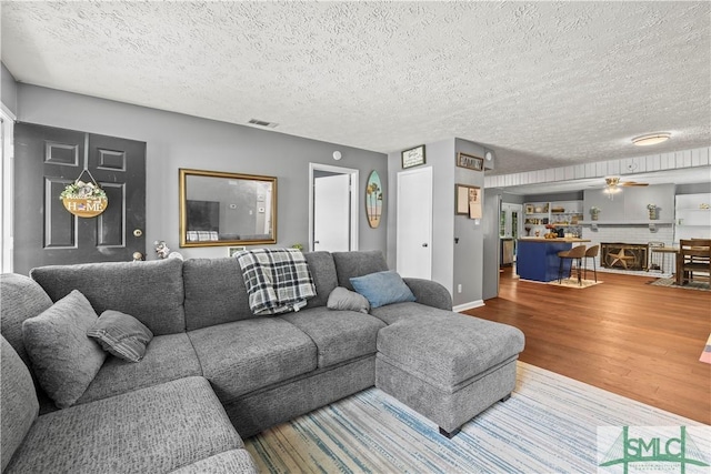81 Quail Ln, Richmond Hill, GA 31324 - living room featuring wood finished floors, a ceiling fan, and a textured ceiling