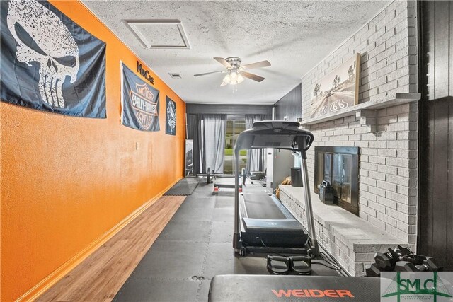 81 Quail Ln, Richmond Hill, GA 31324 - exercise room with baseboards, a ceiling fan, a fireplace, and a textured ceiling