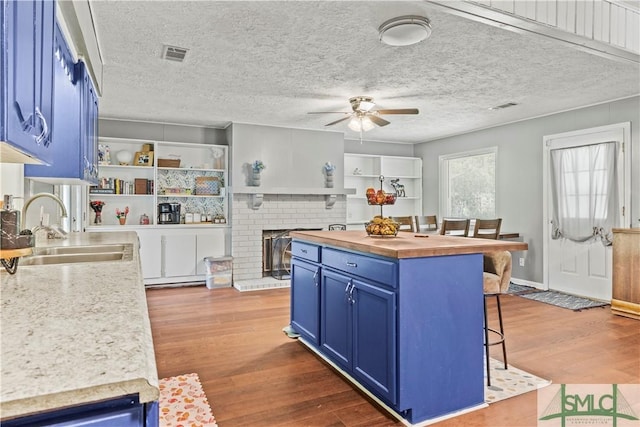 81 Quail Ln, Richmond Hill, GA 31324 - kitchen with blue cabinets, a sink, open shelves, a breakfast bar area, and a ceiling fan