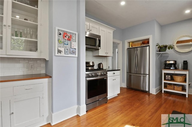 405 E 55th St, Savannah, GA 31405 - kitchen with appliances with stainless steel finishes, tasteful backsplash, white cabinetry, light wood-style flooring, and dark countertops