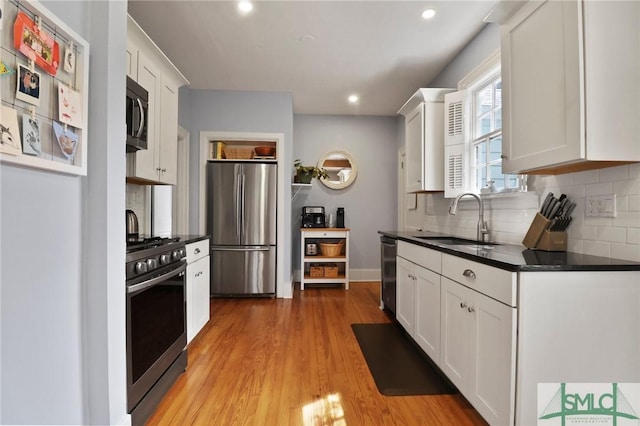 405 E 55th St, Savannah, GA 31405 - kitchen featuring stainless steel appliances, a sink, dark countertops, decorative backsplash, and light wood-type flooring