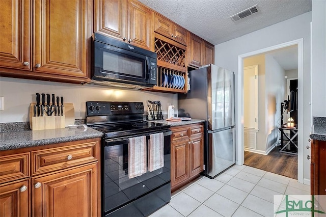 105 Pointe S Dr, Hinesville, GA 31313 - kitchen featuring black appliances, brown cabinets, light tile patterned floors, dark stone counters, and a textured ceiling