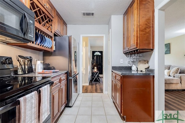 105 Pointe S Dr, Hinesville, GA 31313 - kitchen featuring black appliances, brown cabinets, light tile patterned floors, and a textured ceiling