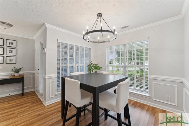 21 Carlisle Ln, Savannah, GA 31419 - dining space featuring a chandelier, light wood-style floors, a decorative wall, ornamental molding, and a textured ceiling