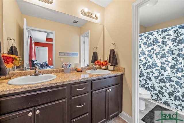 ensuite bathroom featuring double vanity, toilet, tile patterned floors, and curtained shower