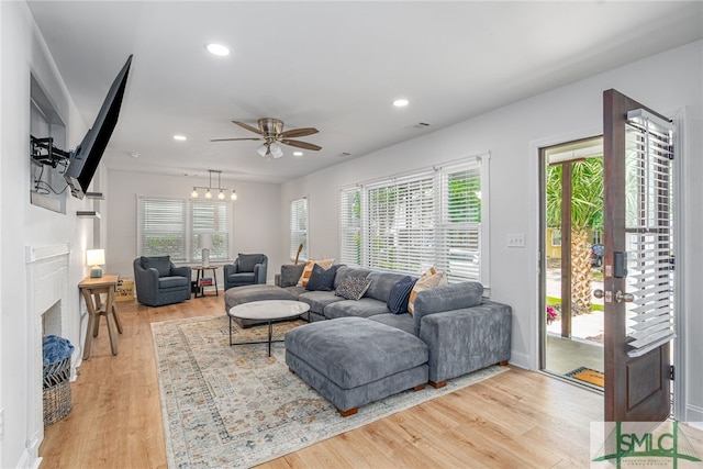 living area with light wood finished floors, recessed lighting, ceiling fan, a fireplace, and baseboards