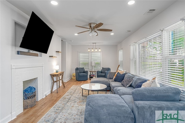 living area with ceiling fan, recessed lighting, light wood finished floors, baseboards, and a brick fireplace