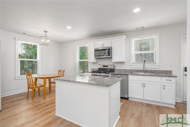 kitchen featuring stainless steel appliances, a sink, white cabinets, light wood-style flooring, and recessed lighting