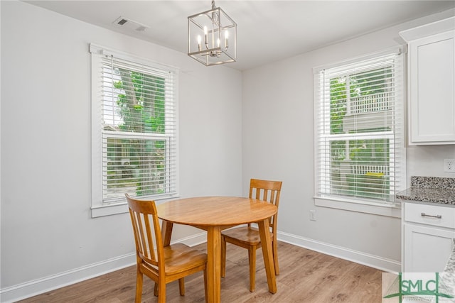 dining area featuring a chandelier, light wood finished floors, healthy amount of natural light, and baseboards