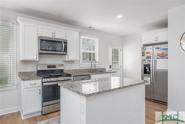kitchen with appliances with stainless steel finishes, a sink, light wood-style floors, light stone counters, and recessed lighting