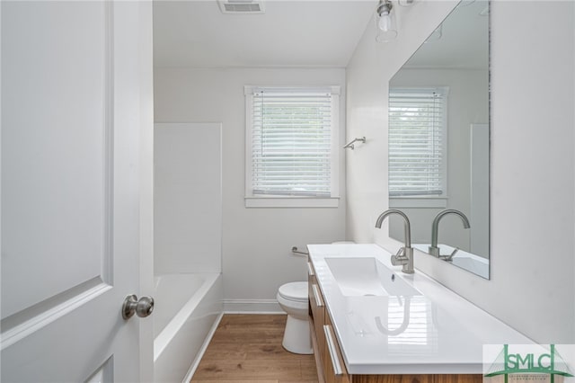 bathroom with vanity, toilet, wood finished floors, and baseboards