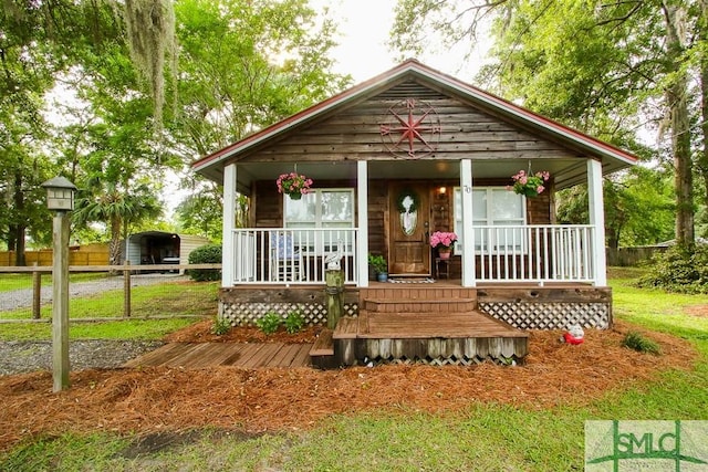 view of front of home with a porch, a detached carport, and fence