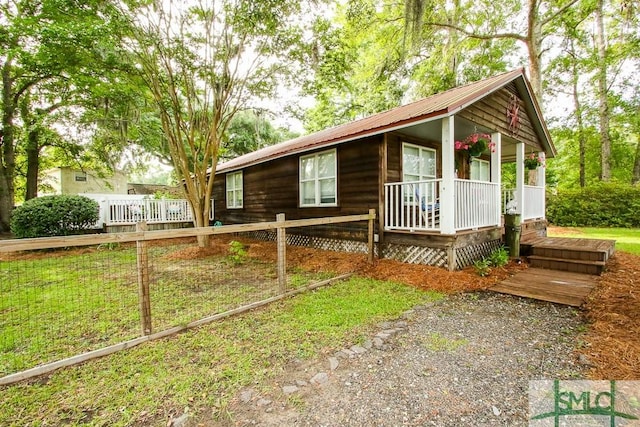 view of front facade with a porch, fence, and metal roof