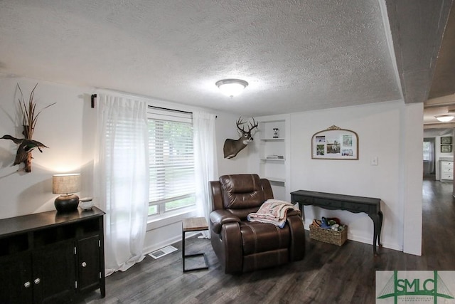 sitting room with dark wood-style flooring, baseboards, and a textured ceiling