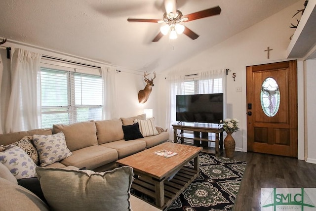 living area featuring vaulted ceiling, plenty of natural light, a ceiling fan, dark wood-type flooring, and baseboards