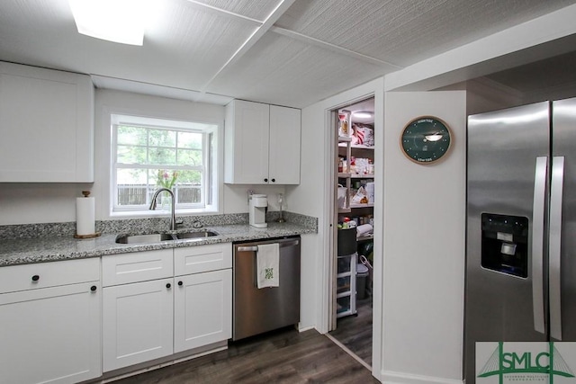 kitchen featuring stainless steel appliances, a sink, dark wood-style flooring, white cabinets, and light stone counters