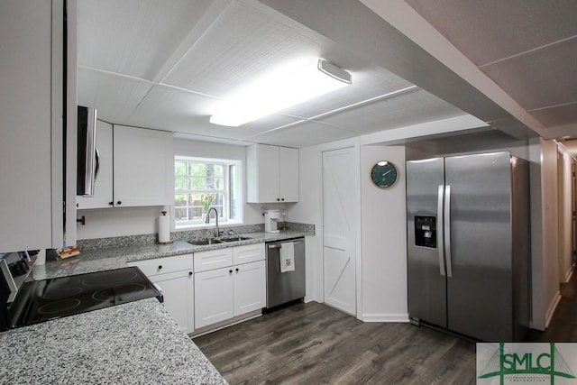 kitchen with appliances with stainless steel finishes, a sink, dark wood-style flooring, white cabinetry, and light stone counters
