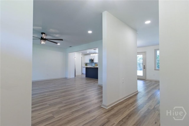 hallway featuring light wood-style floors, recessed lighting, and baseboards