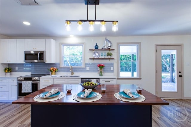 kitchen with stainless steel appliances, a sink, decorative backsplash, white cabinets, and recessed lighting