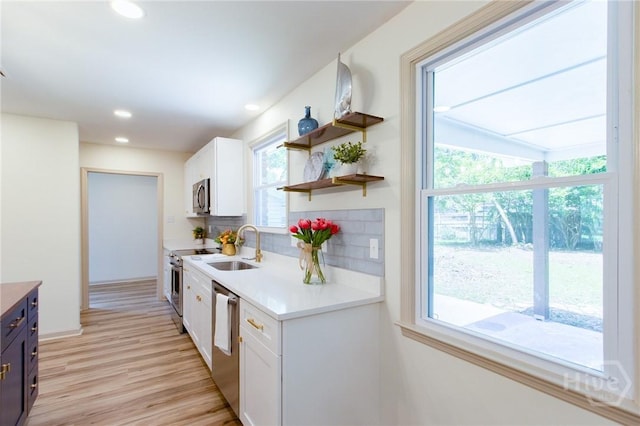 kitchen featuring stainless steel appliances, white cabinetry, light countertops, light wood-type flooring, and open shelves