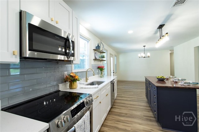 kitchen with stainless steel appliances, a sink, wooden counters, light wood-type flooring, and white cabinetry