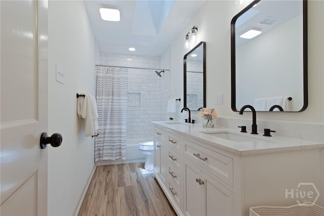 bathroom with wood finished floors, toilet, shower / bath combination with curtain, and double vanity