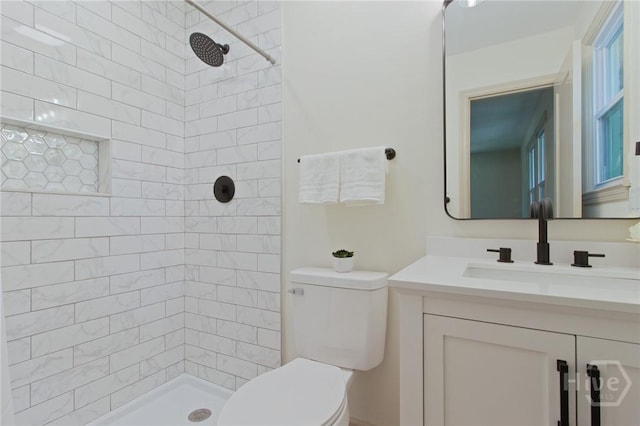 bathroom featuring toilet, a tile shower, and vanity