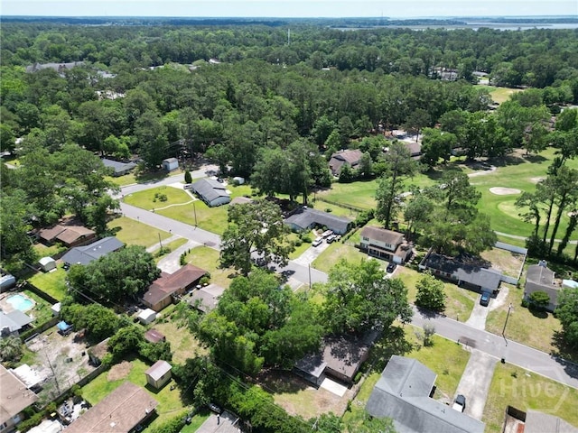 aerial view of property's location featuring a forest and nearby suburban area