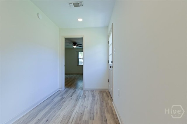 hallway featuring light wood finished floors, baseboards, and recessed lighting